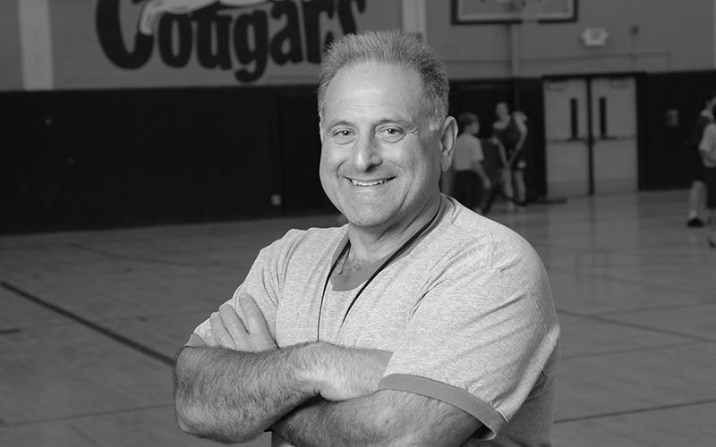 man standing smiling in a school gym