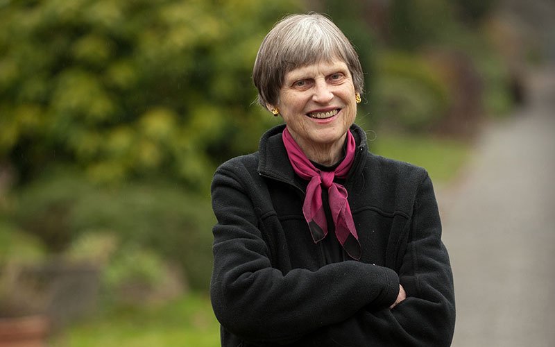 woman in pink scarf smiles at camera